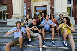 Students sitting together throwing an O