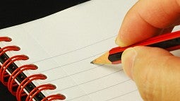 Hand taking notes with a pencil on a notebook Hand taking notes with a pencil on a notebook